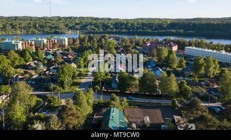 Russian village with wooden houses. Svir river and summer green forests of Leningrad region, Russia. Flying over roofs. Stock Photo