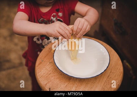 A toddler cracking a farm fresh egg into a bowl. Stock Photo