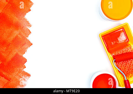 plastic tins with red and yellow paints, paint tray and roller on white painted surface flat view Stock Photo