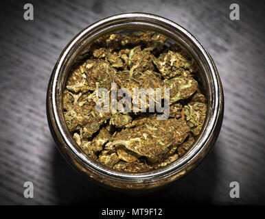 Glass jar full of marijuana on wooden black table Stock Photo