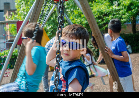 A young boy play on swings in the children's playground in Bachelors Acre in Windsor, UK. Stock Photo