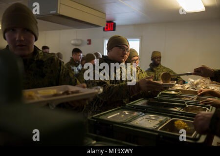 Marines with Task Force Arctic Edge pass through the chow line at Fort Greely, Alaska, March 11, 2018 during exercise Arctic Edge 18. Eating regularly and staying hydrated in a cold weather in environment enables Marines to stay healthy and complete their mission. Arctic Edge 18 is a biennial, large-scale, joint-training exercise that prepares and tests the U.S. military’s ability to operate tactically in the extreme cold-weather conditions found in Arctic environments with more than 1500 participants from the Air Force, Army, Coast Guard, Marine Corps, and Navy utilizing the unique and expans Stock Photo