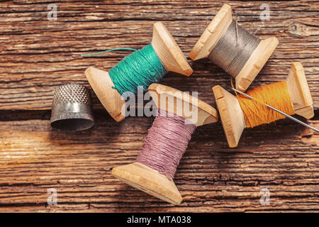 colored threads and thimble on wooden background Stock Photo