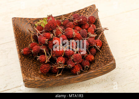 Dry hawthorn heap in the bowl over wooden background Stock Photo