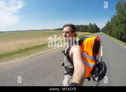 The young man stands in the middle of the highway and looks away, enjoying the fresh air. Stock Photo