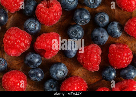 Detail top view on mixed blueberries and raspberries on wooden plate. Stock Photo