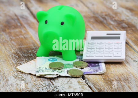 British banknotes and coins, piggy bank and calculator on rustic wooden surface Stock Photo