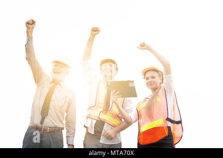 Group of male and female engineers celebration success happiness with raised hands at construction site. Teamwork and success concepts. Isolated on wh Stock Photo