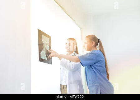 Doctors women discussion and reviewing a resonance magnetic imaging or x ray film checking skull of human head nn examination room. with copy space. Stock Photo