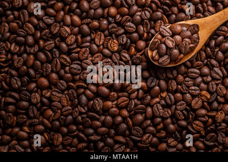 View from above of wooden spoon with coffee lying on coffee beans Stock Photo