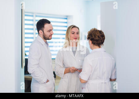 Group of senior doctors and young nurses examining medical report of patient. Team of doctors working together on patients file at hospital. Medical staff analyzing and working at clinic Stock Photo