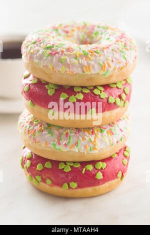 Sweet sprinkled donuts on white kitchen table. Stock Photo