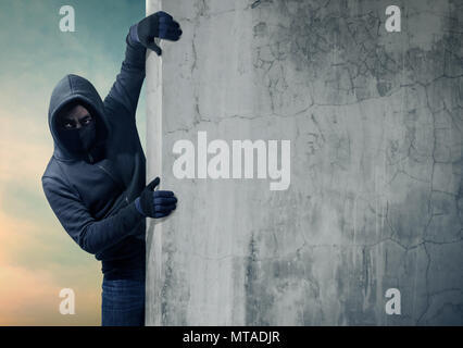 Robber hiding behind a empty wall with space for text Stock Photo