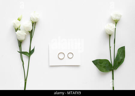Wedding card with wedding rings and roses, on white marble . Top view. Stock Photo