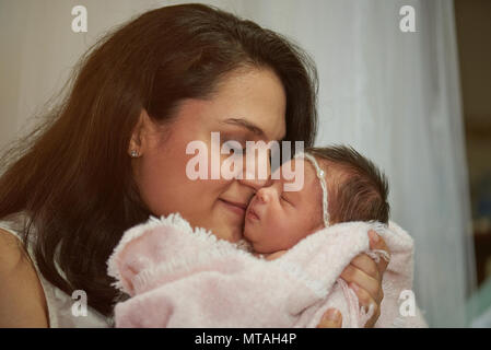 Latina mom hugging newborn baby close up view