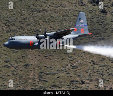 A C130h aircraft loaded with the MAFFS (Modular Airborne Fire Fighting System) from the 152nd Airlift Wing of Reno, Nevada drops a water line while training to contain wildfires just outside Boise, Idaho. April 21, 2017. More than 400 personnel of four C-130 Guard and Reserve units — from California, Colorado, Nevada and Wyoming, making up the Air Expeditionary Group — are in Boise, Idaho for the week-long wildfire training and certification sponsored by the U.S. Stock Photo