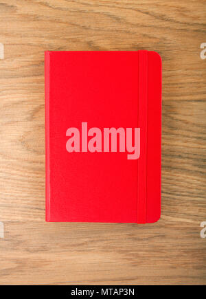 Red copybook with elastic band on wooden background Stock Photo