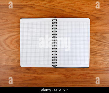 Notepad with a spiral binding and checkered sheets on a wooden background Stock Photo