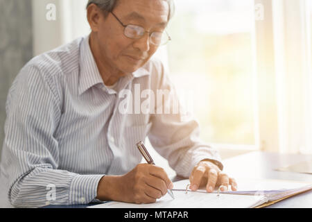 Asian senior working hand writing or sign insurance contract for future concept. Stock Photo
