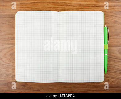 Open blank checked notebook with green pen on a table Stock Photo