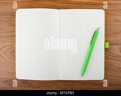 Open blank checked notebook with green pen on a table Stock Photo