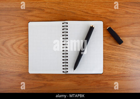 Notepad with a spiral binding and checkered sheets on a wooden background Stock Photo