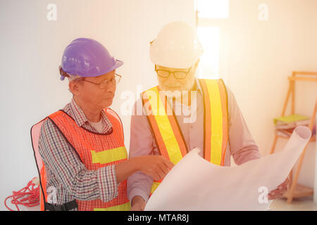 two engineers looking at blueprint to planning construction project Stock Photo