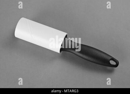 A lint brush with Black Handle used to remove excess fabric and particles from cloth on a grey background Stock Photo