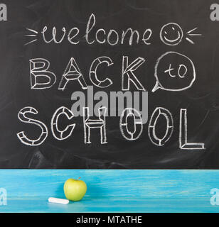 Still life with chalk and apple against blackboard with 'welcome back to school' on background Stock Photo