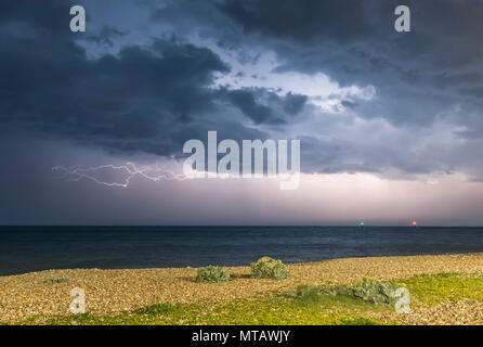 Lightning strike over the sea at night, with dark moody storm clouds, over the British south coast in England, UK. Stock Photo
