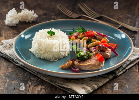Sichuan pork, broccoli, red pepper and cashew stir-fry with rice Stock Photo