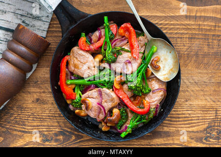 Sichuan pork, broccoli, red pepper and cashew stir-fry in a frying pan - top view Stock Photo