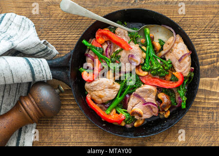 Sichuan pork, broccoli, red pepper and cashew stir-fry in a frying pan - top view Stock Photo