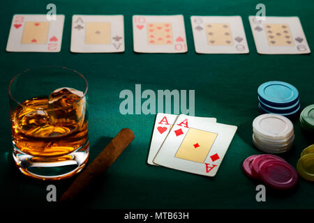 Texas hold'em poker with a hand of two aces, chips, cigar, and glass of whiskey on green broadcloth. Won by three aces. Stock Photo