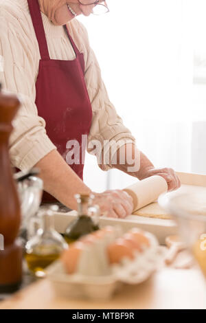 Happy old woman using rolling pin in her kitchen Stock Photo