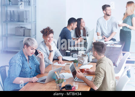 Coworkers enjoying their time at work chatting, and drinking coffee Stock Photo