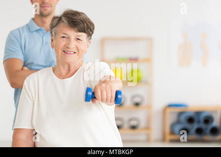 Elderly woman doing active, isometric exercises guided by physical therapist at the hospital rehabilitation center Stock Photo