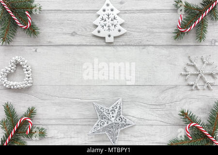 Christmas background with fir tree twigs, candy canes, white stars, christmas tree, christmas decoration and a heart out of bells on wood. Stock Photo