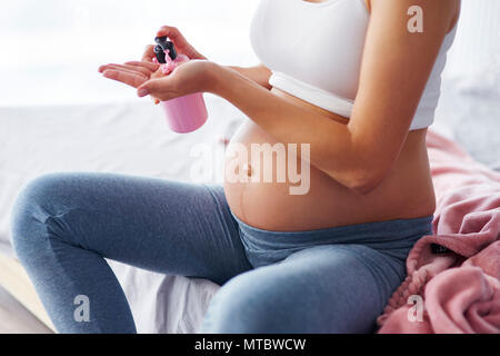 Pregnant woman applying moisturizer on her belly Stock Photo