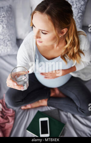 Worried pregnant woman drinking water Stock Photo