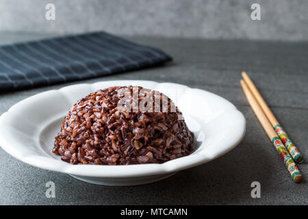 Cooked Black Rice in white Plate with Chopsticks. Traditional Organic Food. Stock Photo