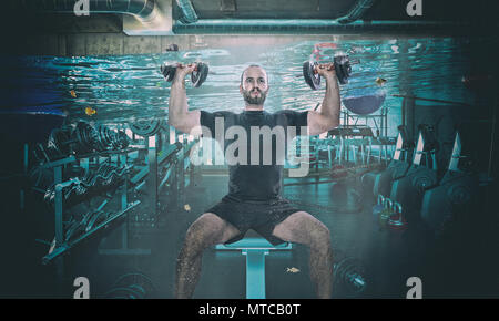 funny image of man training with dumbbell in a flooaded gym Stock Photo
