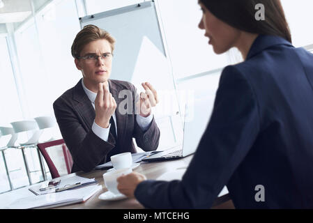 Businessman and businesswoman at office working together sitting at table drinking hot coffee discussing project concentrated woman close-up Stock Photo