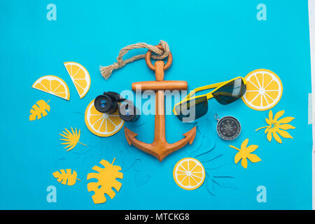 Sea travel background with sunglasses, binoculars, anchor, compass and tropical leaves on a bright blue background. Summer vacation concept with copy  Stock Photo