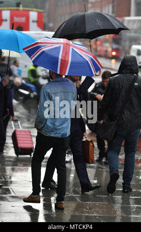 People get caught in a downpour in Victoria, central London, as forecasters have warned of the risk of more flooding, travel disruption and power cuts with thunderstorms set to rumble on. Stock Photo