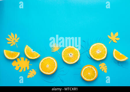 Lemon slices and tropical leaves pattern on a bright blue background. Papercraft flat lay header. Stock Photo
