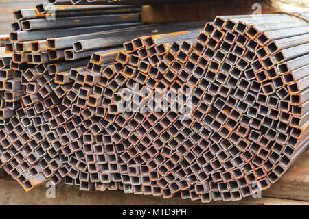 Metal square pipes connected together. The pipes are covered with rust. Outdoor storage Stock Photo
