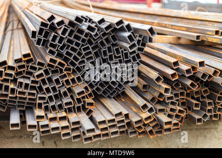 Metal square pipes connected together. The pipes are covered with rust. Outdoor storage Stock Photo