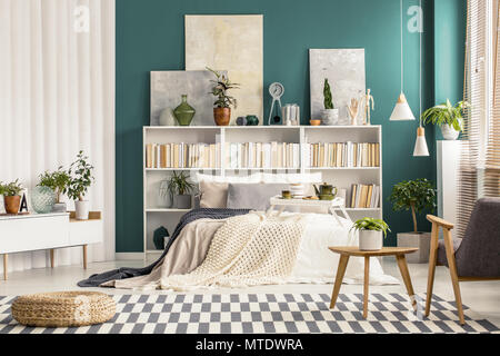 Checkered rug and modern wooden furniture in a stylish bedroom interior for art and nature lover Stock Photo