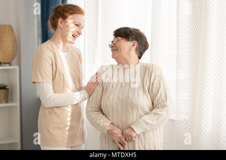 Smiling nurse taking care of a happy elderly woman in a nursing home Stock Photo